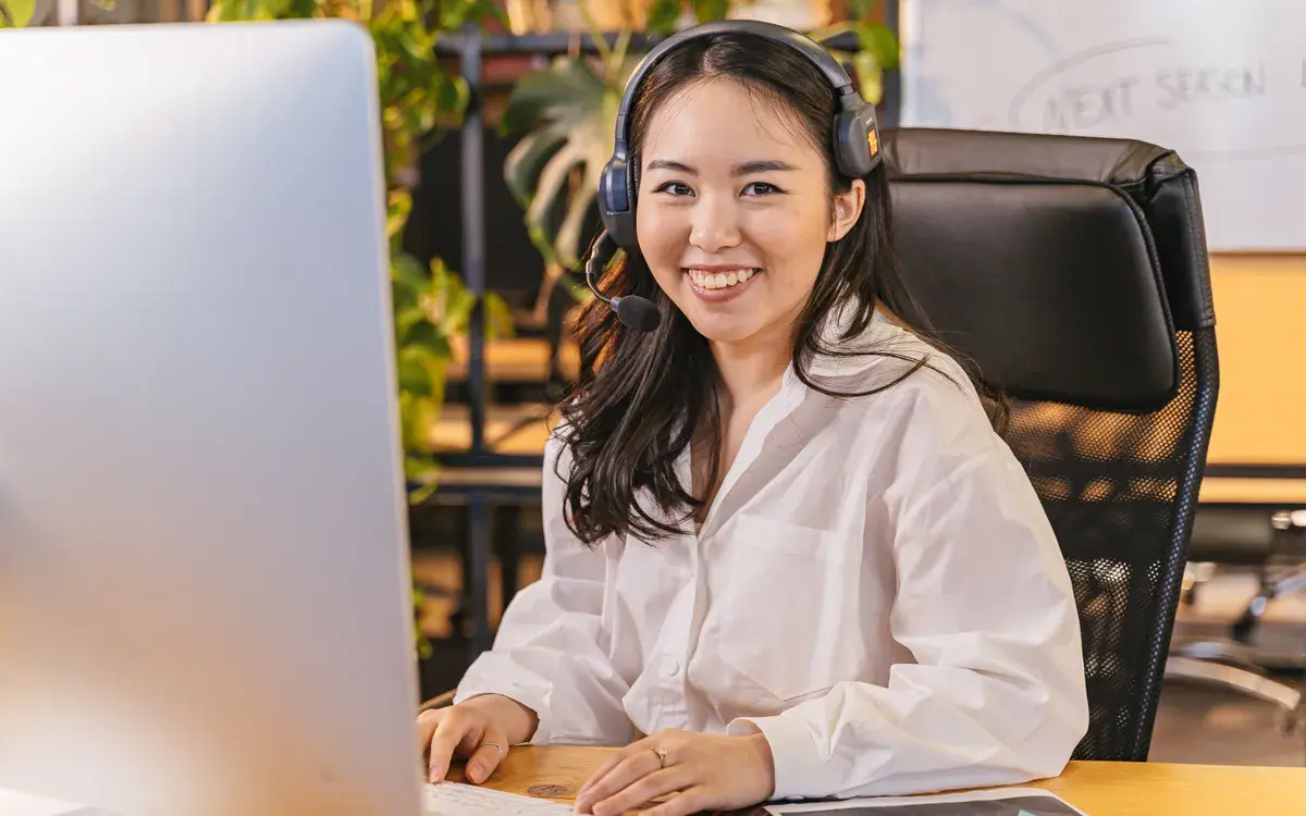 Someone wearing a headset at a desk, smiling as they talk a professional through setting up their profile.