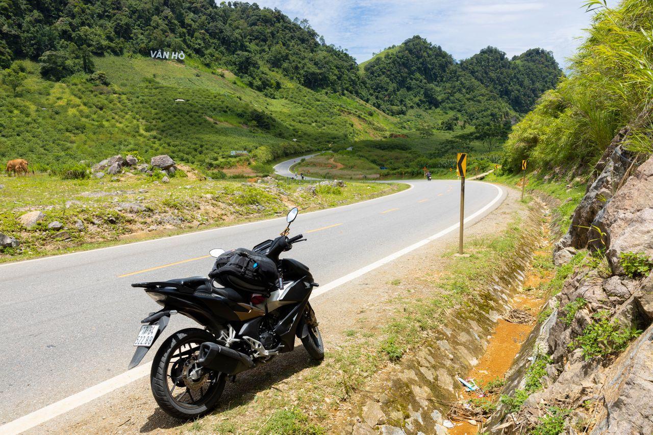 A motorbike parked on the side of a Vietnamese mountain road.
