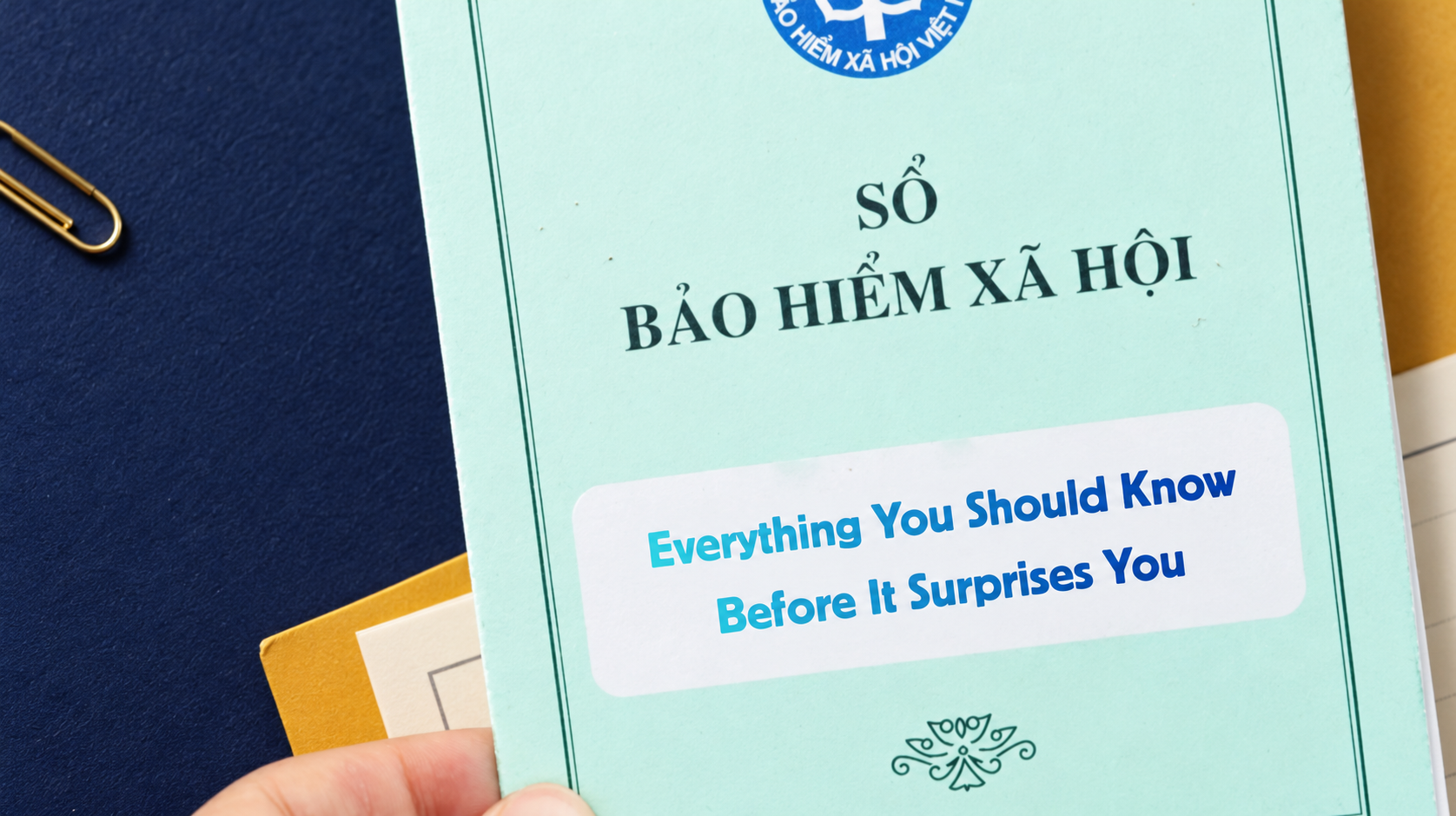 A hand holds a pale green Vietnamese social insurance booklet stamped Sổ Bảo hiểm xã hội